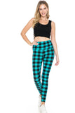 Woman wearing black crop top and teal plaid high-waisted leggings, smiling at camera. Bright, stylish activewear ensemble showcasing comfortable fit and trendy pattern.