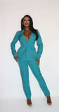 Stylish teal powersuit with rhinestone-embellished blazer and matching pants, worn by a woman with long dark hair posing confidently against a white background